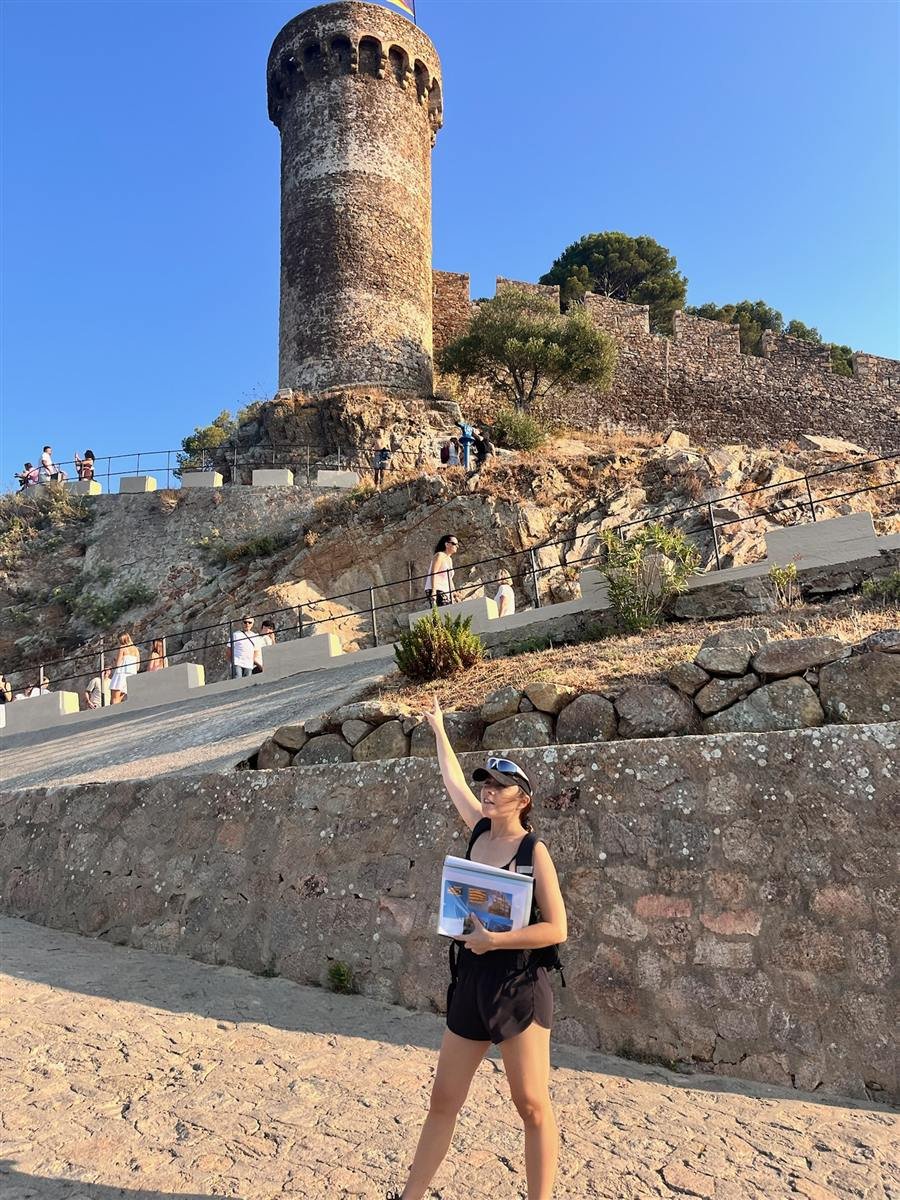 Júlia guiando a un grupo junto a la torre de la Vila Vella en Tossa de Mar
